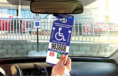 Handicapped vehicle permit hanging from rear-view mirror in vehicle